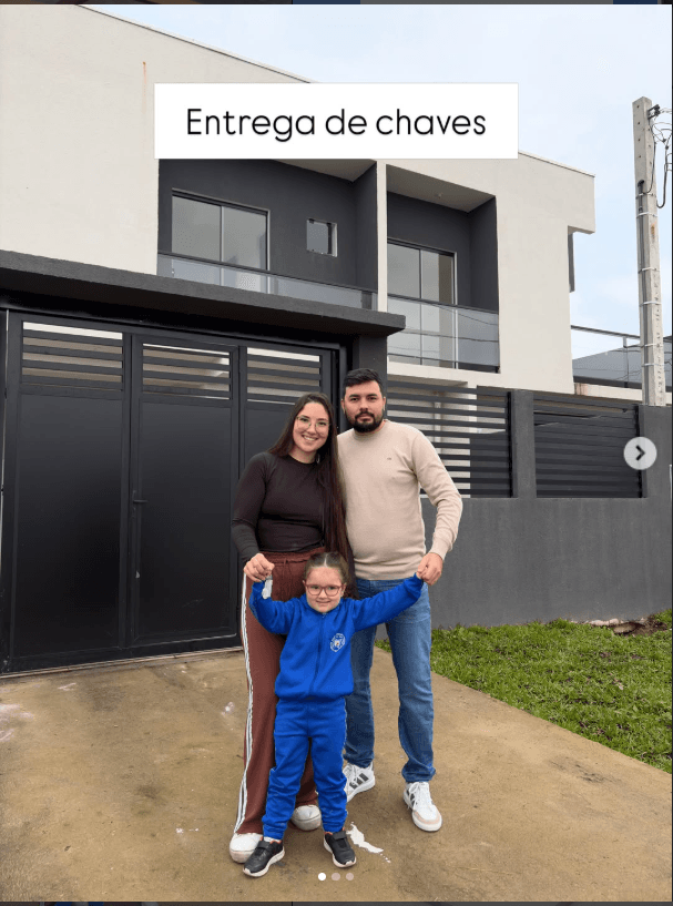 Família em frente ao novo lar durante a entrega das chaves